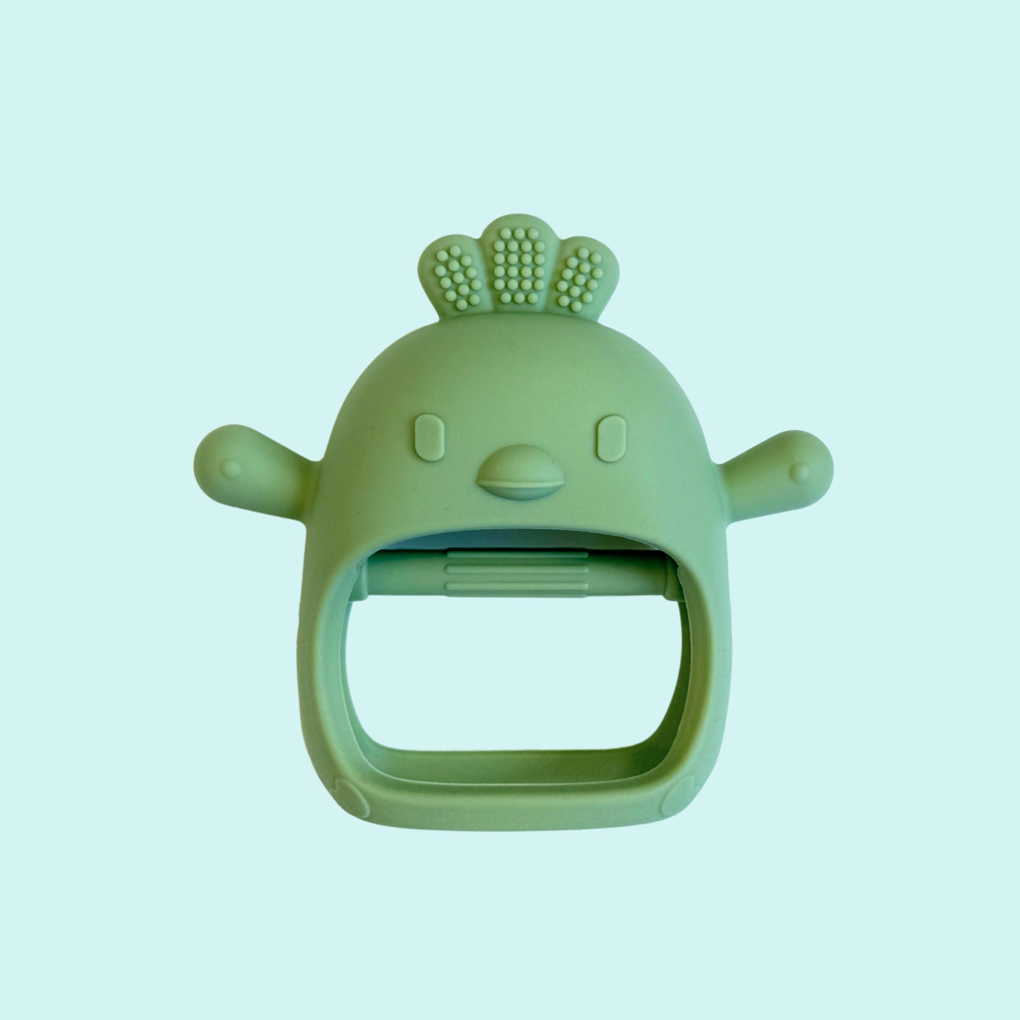 Green silicone teether shaped like a cheerful chicken with textured comb and wings, easy-grip handle for soothing baby’s gums