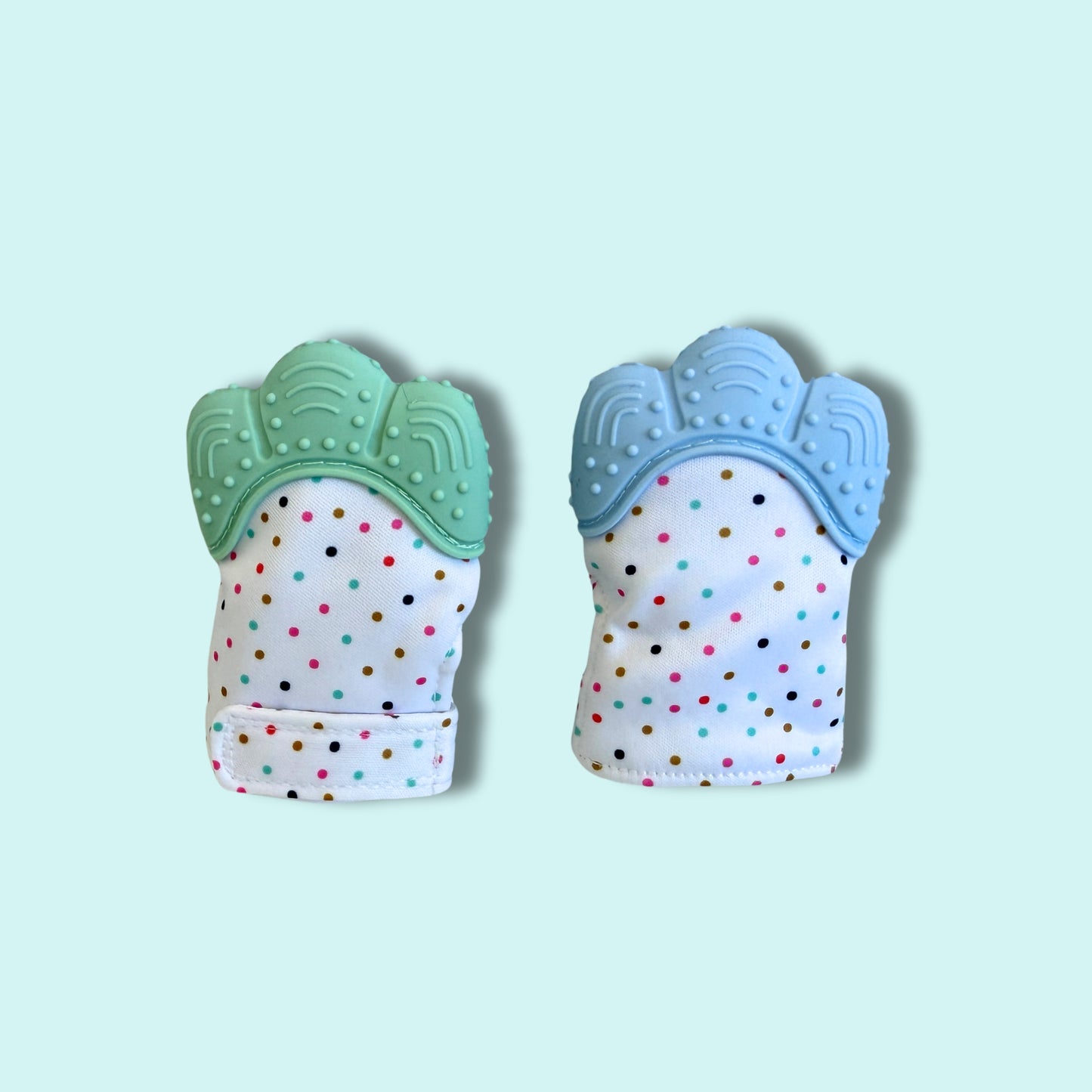 Pair of baby teething mittens with soft, textured silicone tops in green and blue, and colourful polka-dot fabric base for safe self-soothing