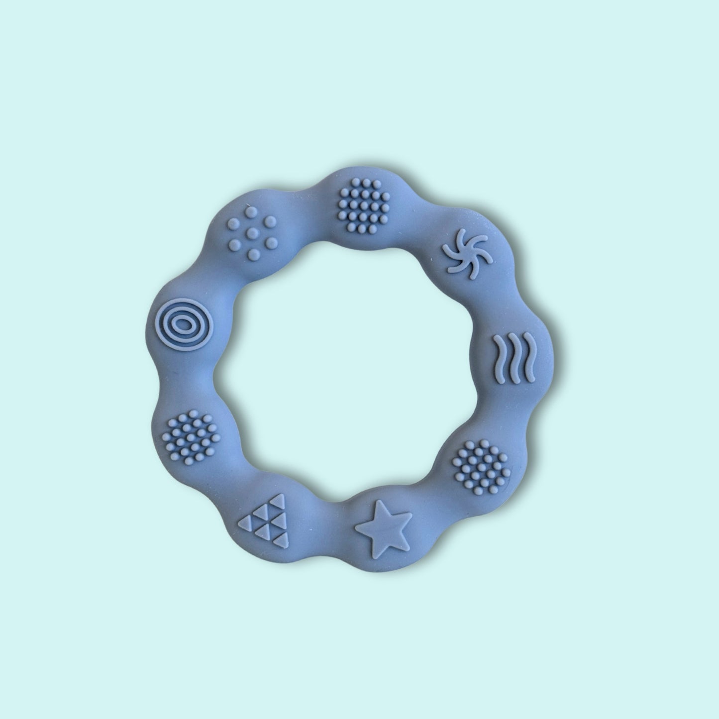 Grey silicone textured ring teether with raised sensory patterns designed to soothe sore gums and encourage fine motor exploration for babies