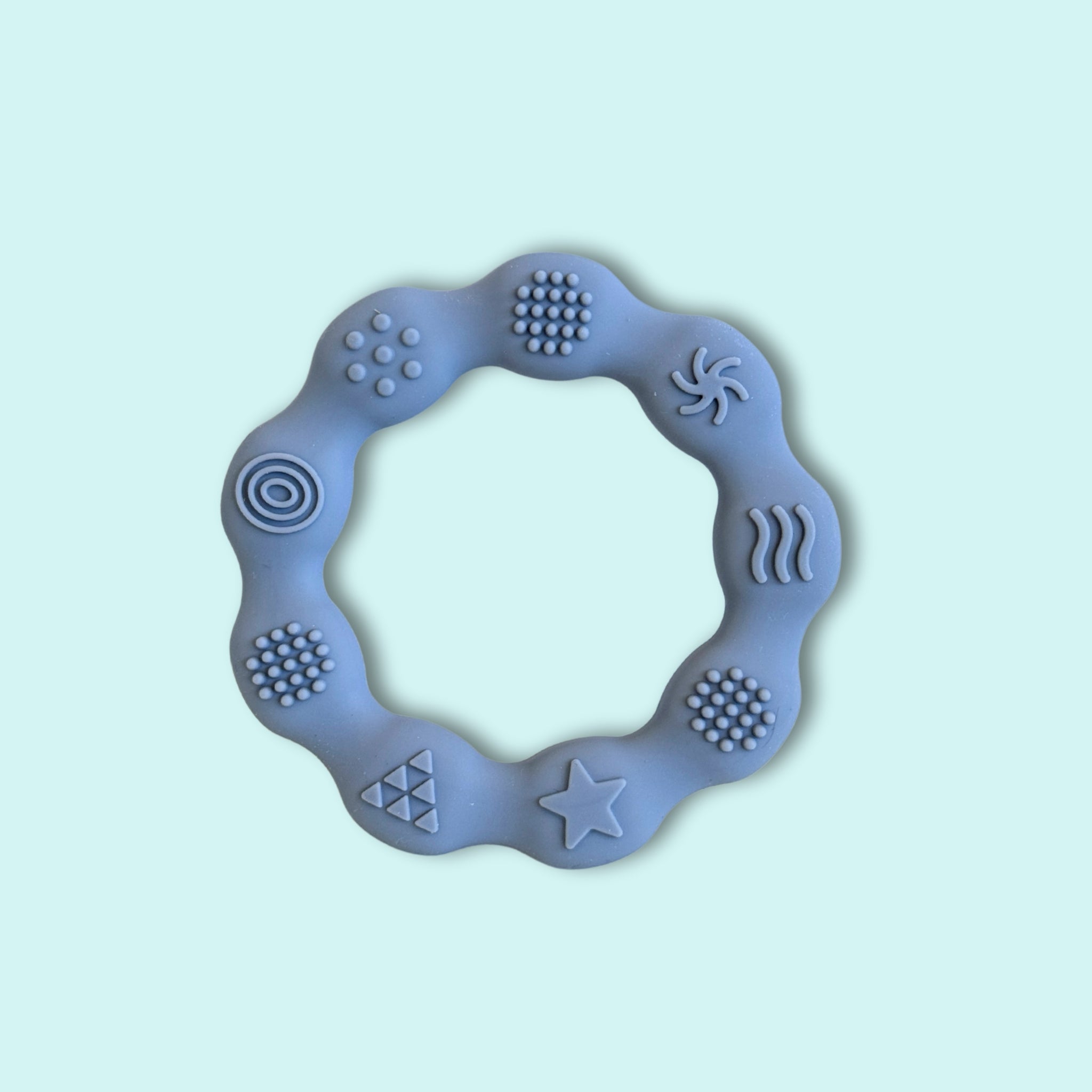 Grey silicone textured ring teether with raised sensory patterns designed to soothe sore gums and encourage fine motor exploration for babies